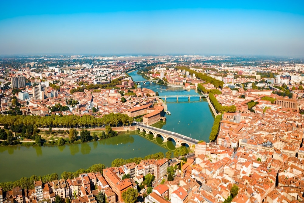 Vue aérienne de Toulouse avec le Pont Neuf, la Garonne et les emblématiques toits en brique rose de la ville rose.