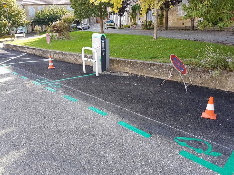 Installation Borne Recharge Électrique eVlink en Village Borne de recharge e-Vlink et place de stationnement pour voiture électrique marquée en vert avec cônes de chantier.