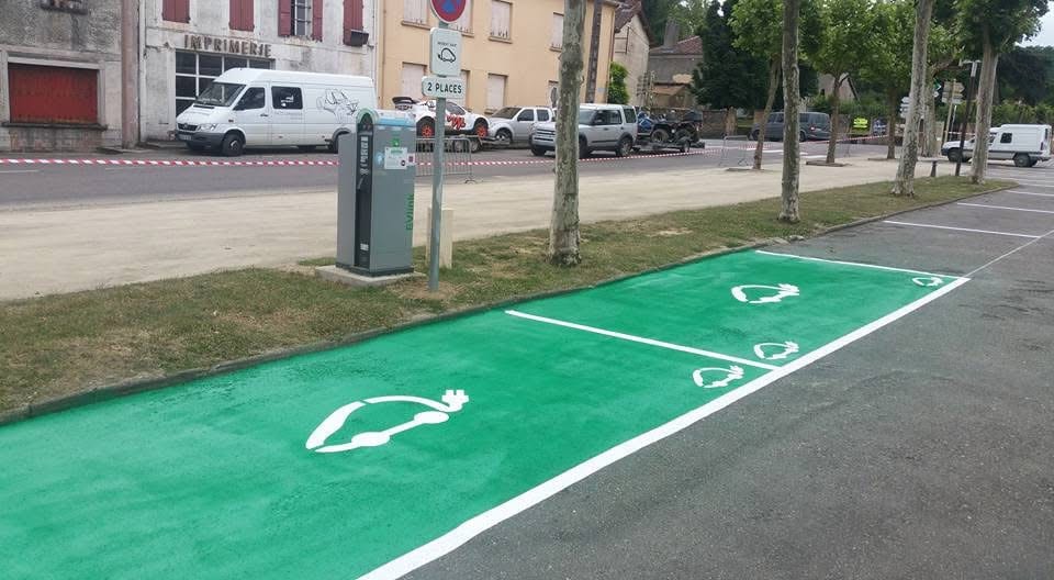 Borne de recharge et parking pour voiture électrique Deux places de parking vertes réservées aux voitures électriques avec borne de recharge EVlink et marquages au sol.